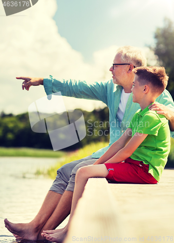 Image of grandfather and grandson sitting on river berth