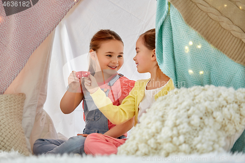 Image of little girl playing tea party in kids tent at home