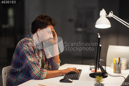 Image of creative man with computer working at night office