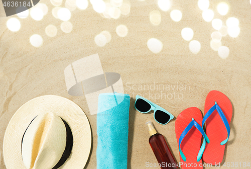 Image of straw hat, flip flops and sunglasses on beach sand