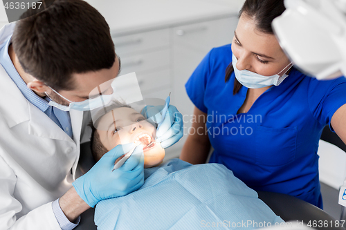 Image of dentist checking for kid teeth at dental clinic