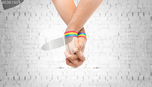 Image of hands of couple with gay pride rainbow wristbands