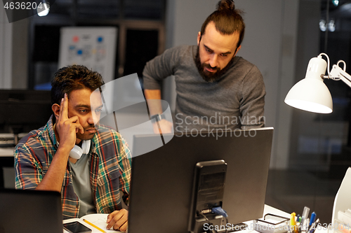 Image of creative team with computer working late at office