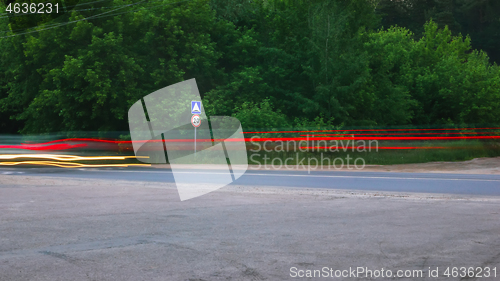 Image of Blurred Glowing Lines of Headlights and Traffic Sign on the Coun