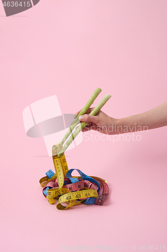 Image of Woman\'s hand with asparagus sticks is taking measuring tapes.