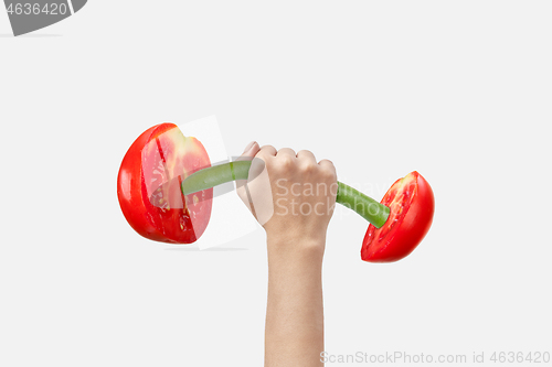 Image of Woman hand holds sport barbell made from natural cut tomatoes.