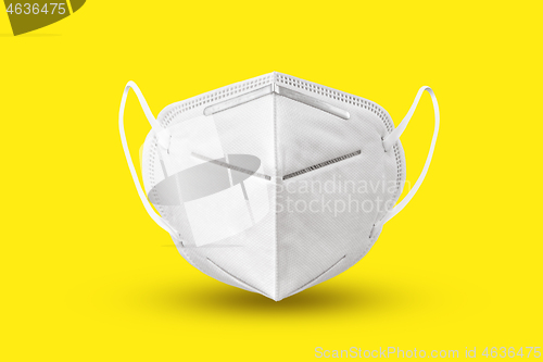 Image of Floating medical mask above yellow background with soft shadows.