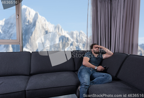 Image of young casual man using a mobile phone at home