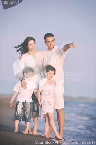 Image of happy young family have fun on beach at sunset