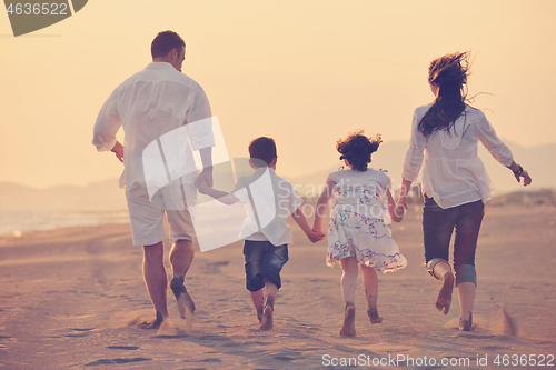 Image of happy young family have fun on beach at sunset