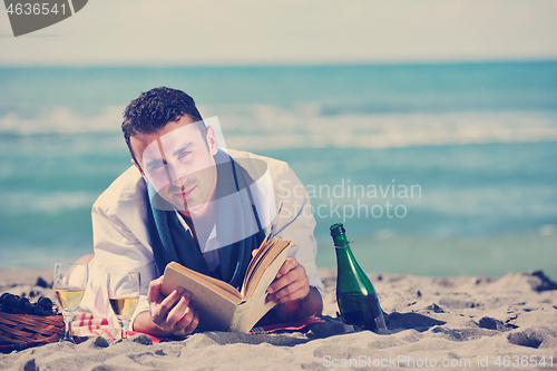 Image of man reading book at beach