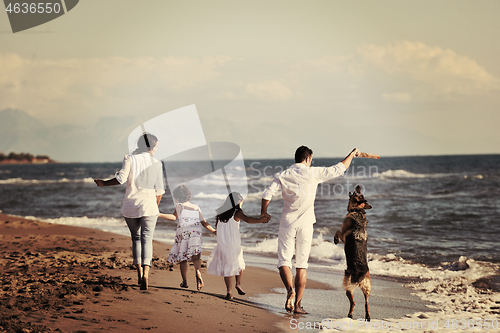 Image of happy family playing with dog on beach