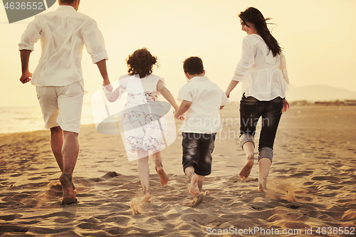 Image of happy young family have fun on beach at sunset