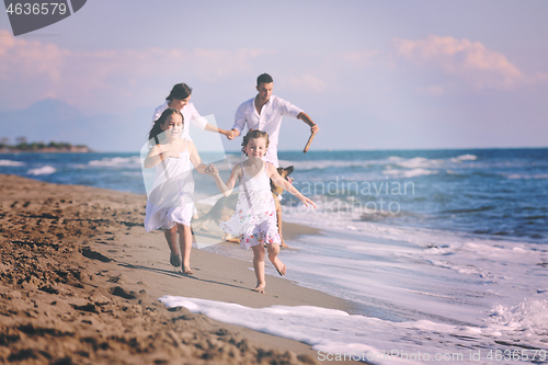 Image of happy family playing with dog on beach