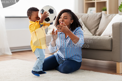 Image of mother and baby playing with soccer ball at home