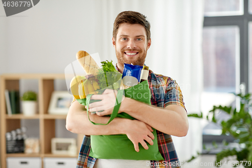 Image of smiling young man with food in bag at home