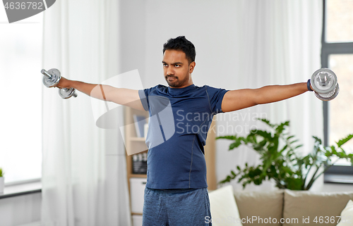 Image of indian man exercising with dumbbells at home