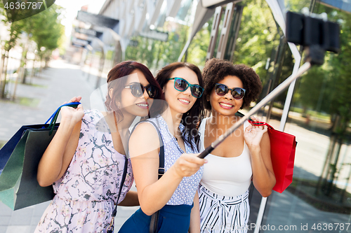 Image of women with shopping bags taking selfie outdoors