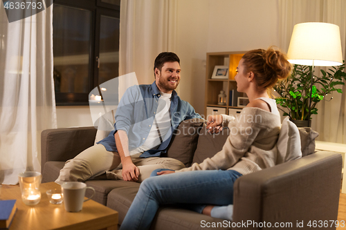 Image of happy couple talking at home in evening