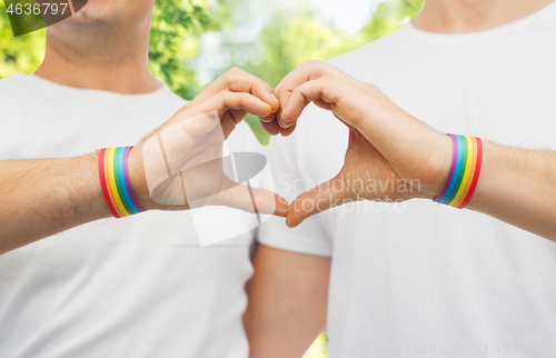 Image of gay couple with rainbow wristbands and hand heart