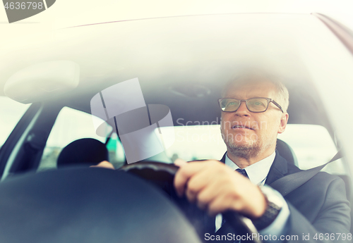 Image of happy senior businessman driving car