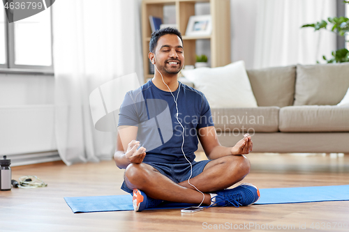 Image of indian man meditating in lotus pose at home