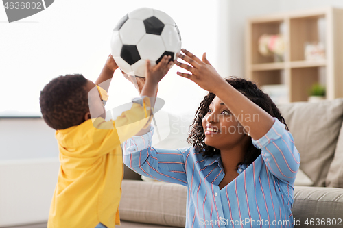 Image of mother and baby playing with soccer ball at home