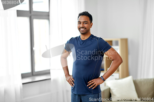 Image of smiling indian man with fitness tracker at home