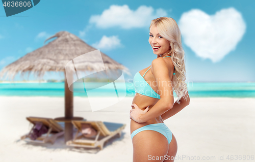 Image of young woman posing in bikini on beach