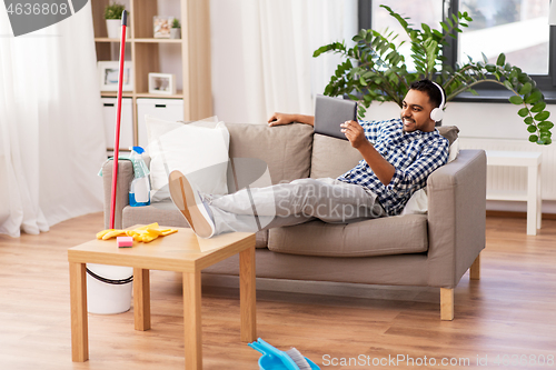 Image of indian man in headphones after cleaning home