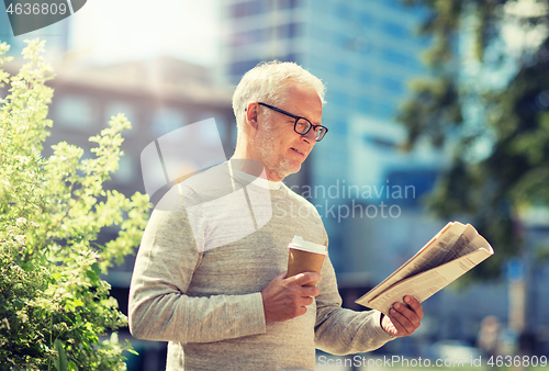 Image of senior man reading newspaper and drinking coffee