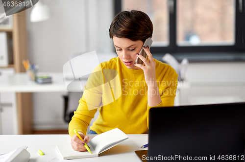 Image of businesswoman calling on smartphone at office