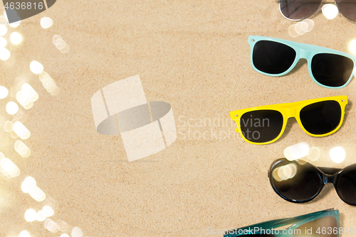 Image of different sunglasses on beach sand