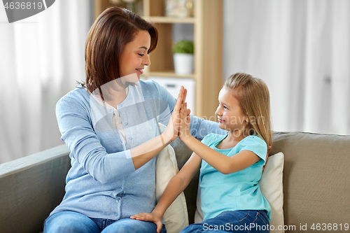 Image of mother and daughter making high five at home