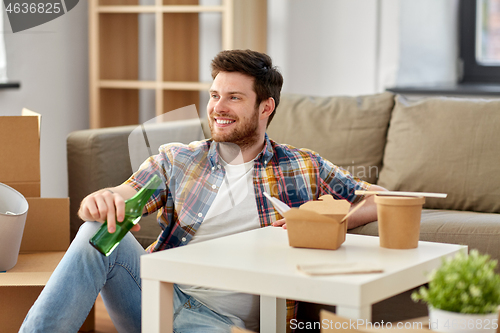 Image of smiling man drinking beer and eating at new home