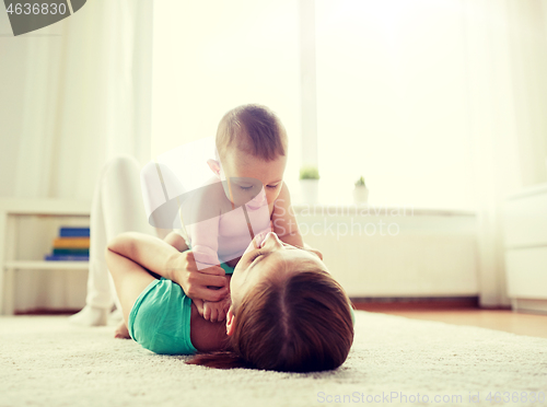 Image of happy mother playing with baby at home