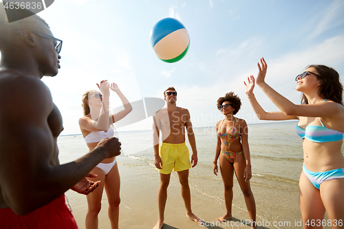 Image of happy friends playing ball on summer beach