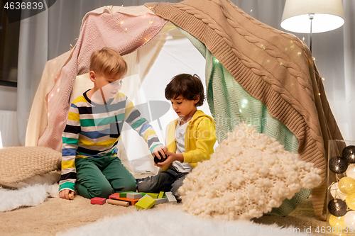 Image of boys playing toy blocks in kids tent at home