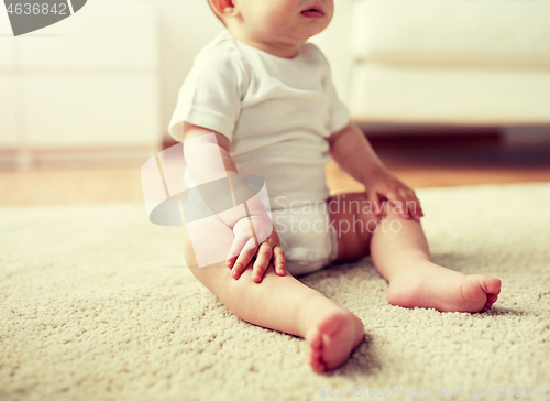 Image of happy baby boy or girl sitting on floor at home