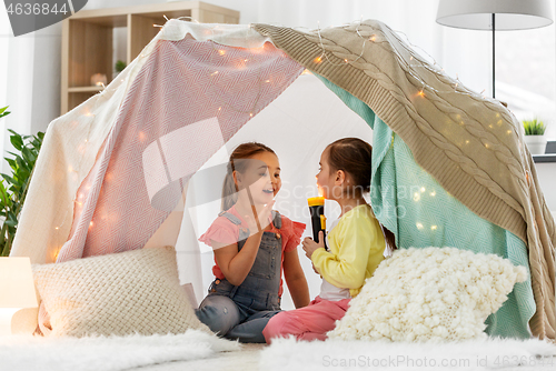 Image of girls playing with torch in kids tent at home