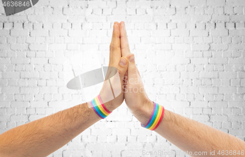 Image of hands with gay pride wristbands make high five