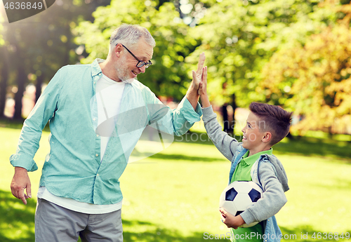 Image of old man and boy with soccer ball making high five