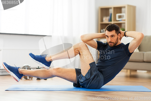 Image of man making bicycle crunch exercise at home