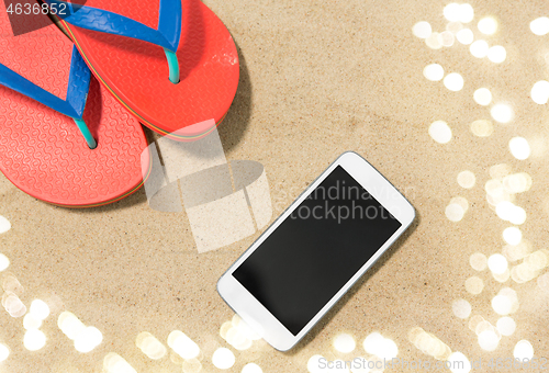 Image of smartphone and flip flops on beach sand