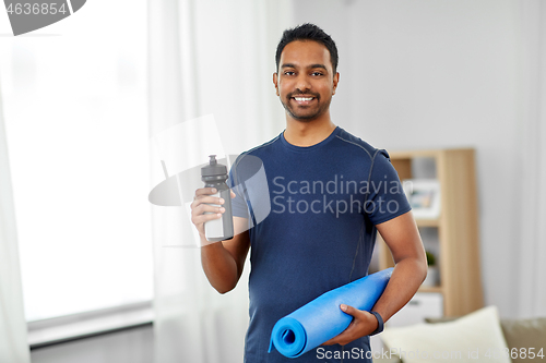 Image of indian man with exercise mat and bottle at home