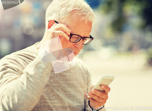 Image of senior man texting message on smartphone in city