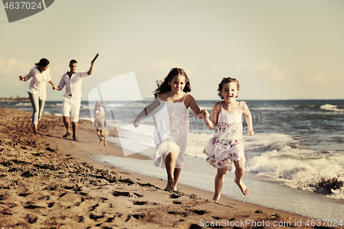 Image of happy family playing with dog on beach