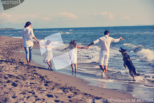 Image of happy family playing with dog on beach