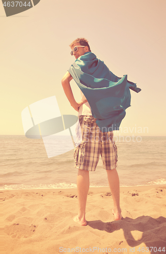 Image of funny superhero standing on beach