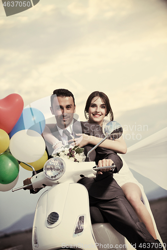 Image of just married couple on the beach ride white scooter